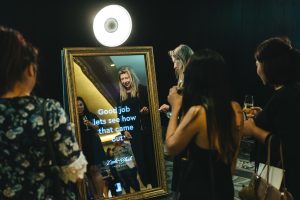 Four ladies standing around a mirror photo booth in Auckland