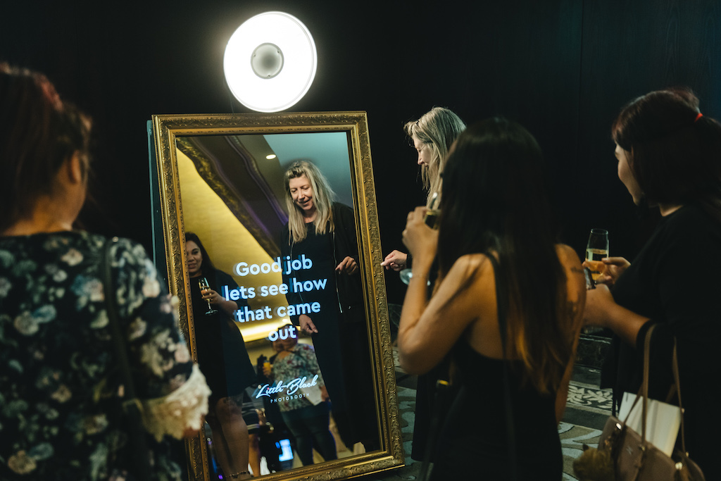 Four ladies standing around a mirror photo booth in Auckland